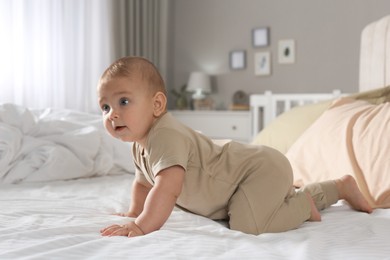 Cute baby crawling on bed at home
