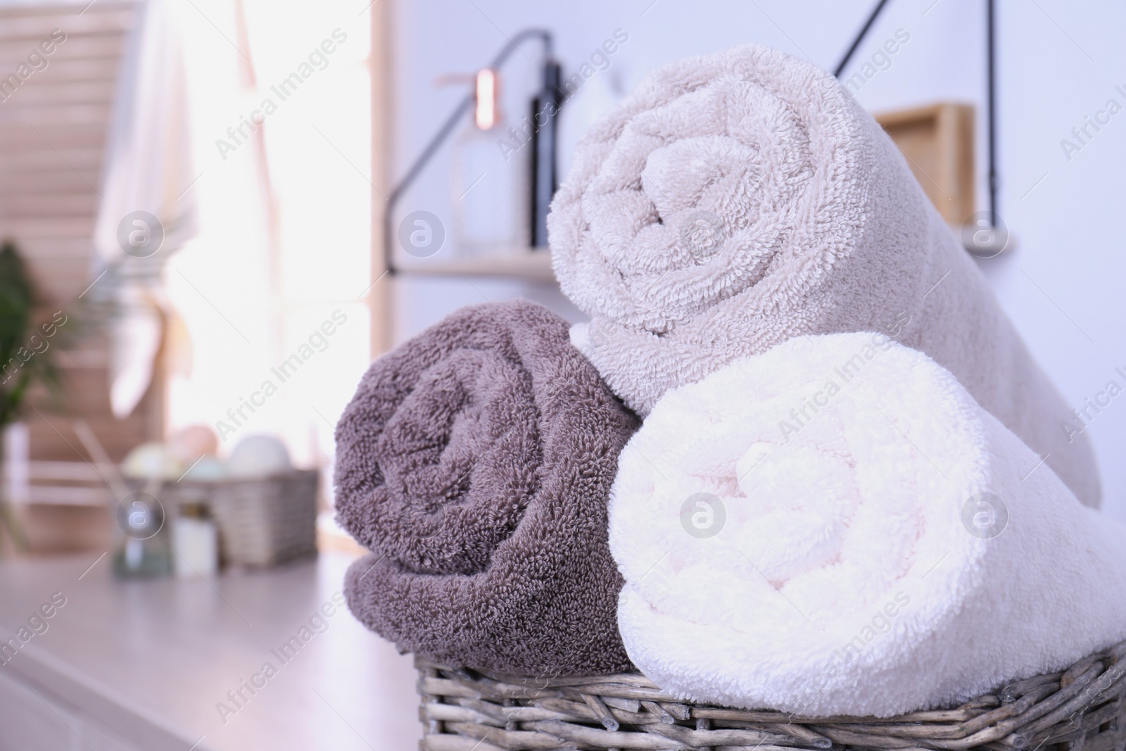 Photo of Basket with rolled fresh towels in bathroom, closeup. Space for text