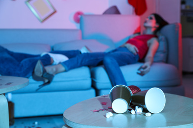 Photo of Drunk friends sleeping after New Year party, focus on messy table