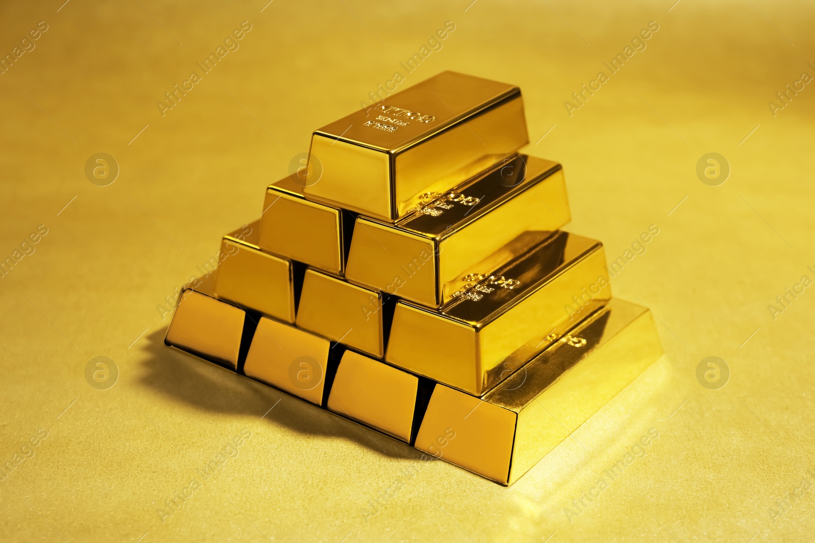 Photo of Many shiny gold bars on color background