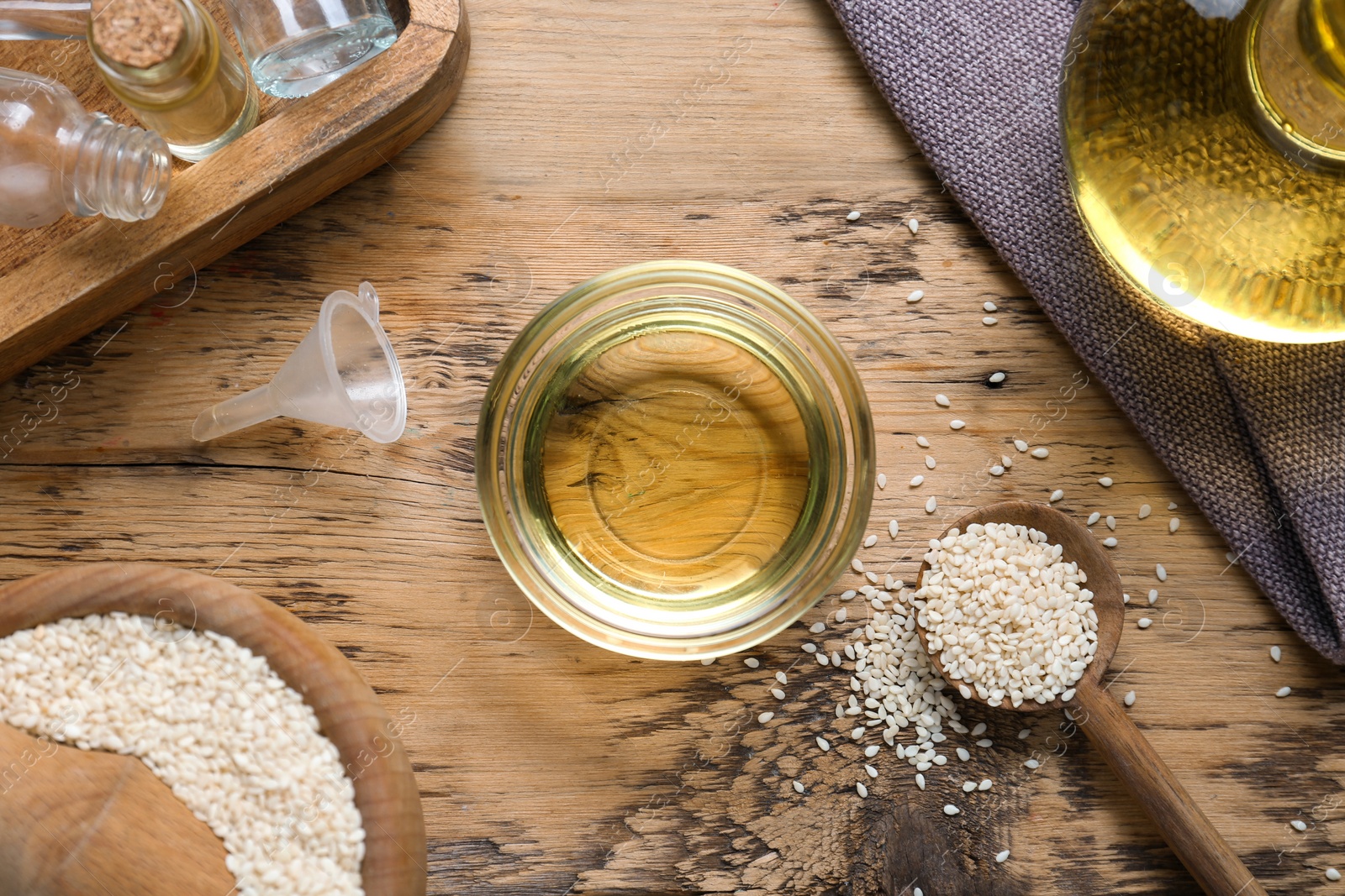 Photo of Sesame oil and seeds on wooden table, flat lay