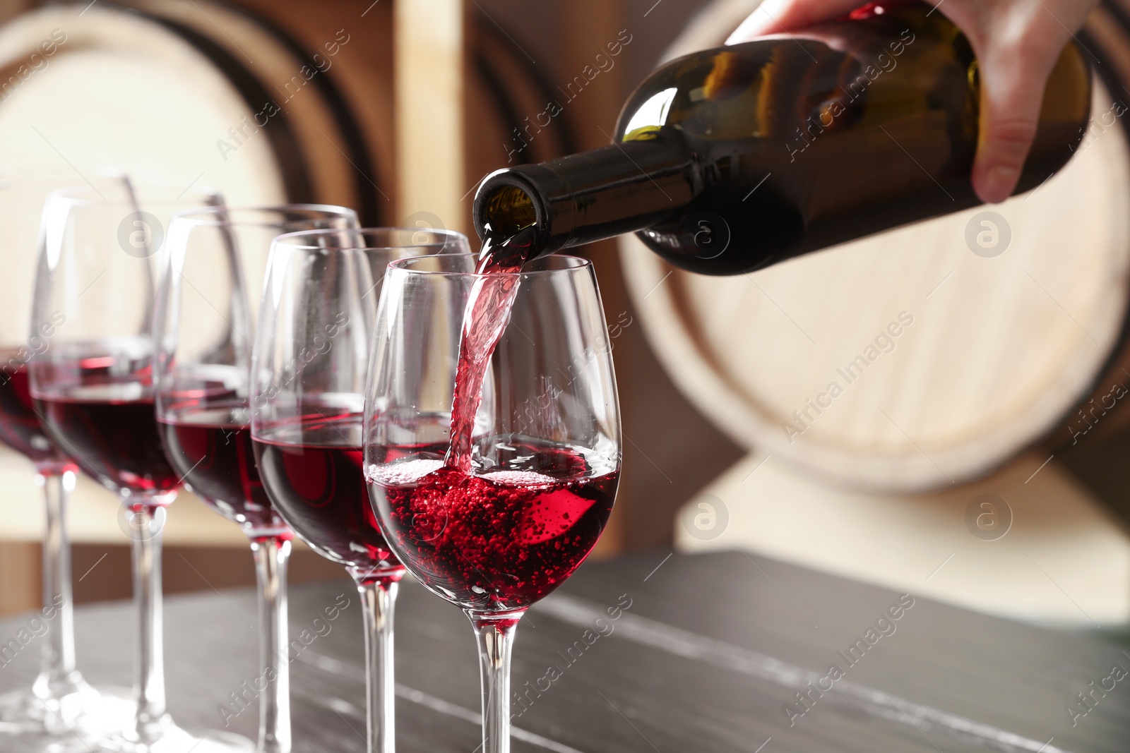 Photo of Woman pouring delicious red wine into glass, closeup