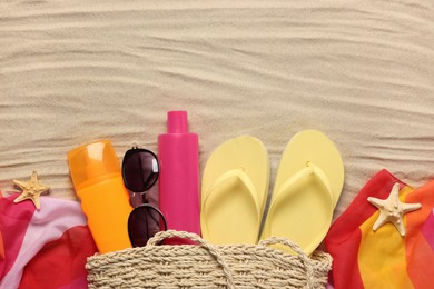Photo of Flat lay composition with wicker bag and other beach accessories on sand. Space for text