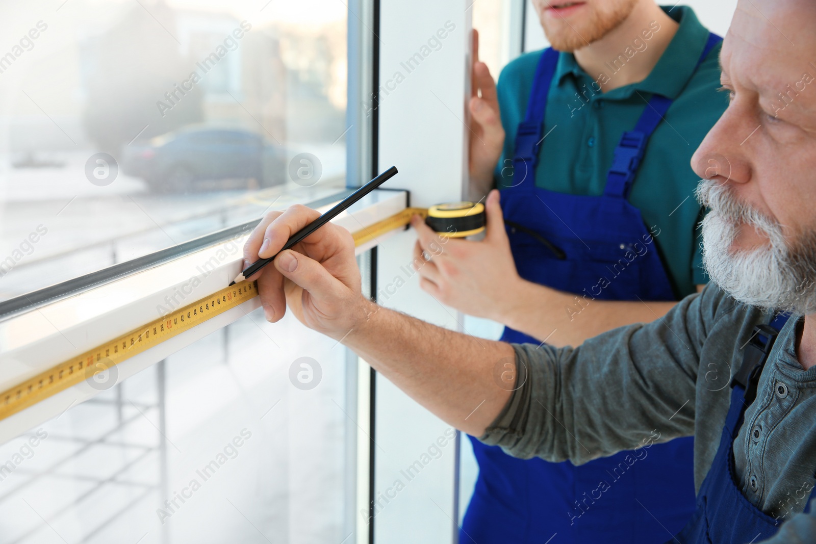 Photo of Service men measuring window for installation indoors