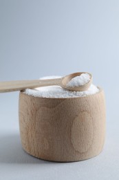 Photo of Organic white salt in bowl and spoon on light grey background, closeup. Space for text