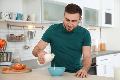 Photo of Young man having breakfast with tasty milk at home