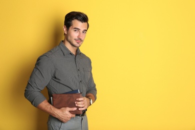 Young male teacher with books on yellow background. Space for text