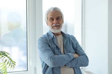 Portrait of happy grandpa with grey hair near window indoors