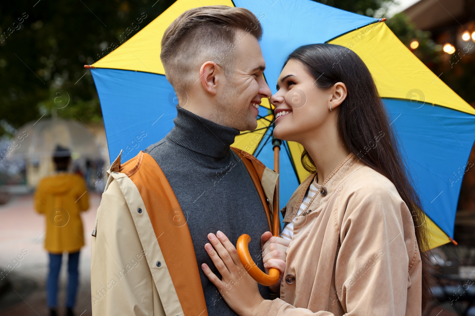 Photo of Lovely young couple with umbrella walking under rain on city street