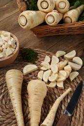 Photo of Whole and cut parsnips on wooden table, above view
