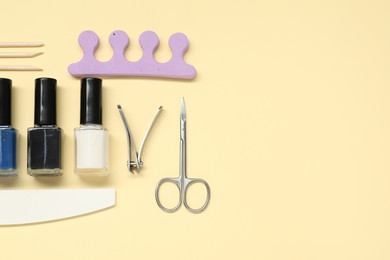 Photo of Nail polishes and set of pedicure tools on beige background, flat lay. Space for text