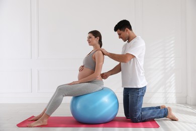 Photo of Husband massaging his pregnant wife in light room. Preparation for child birth