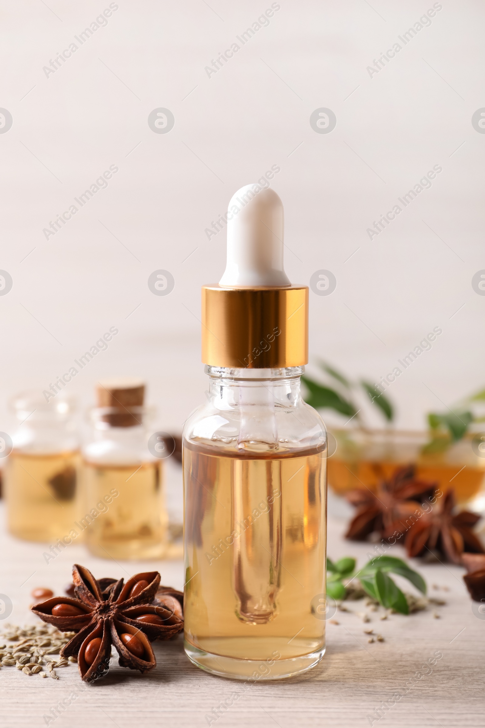 Photo of Bottles of essential oil, anise and seeds on white wooden table