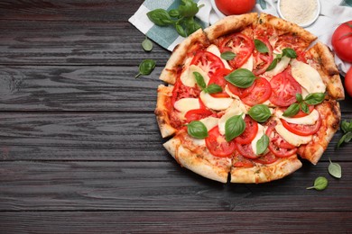 Delicious Caprese pizza on black wooden table, flat lay. Space for text