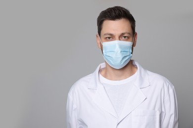 Photo of Doctor or medical assistant (male nurse) in uniform with protective mask on light grey background. Space for text