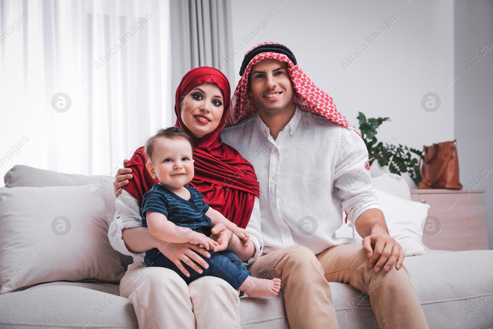 Photo of Happy Muslim family with little son in living room