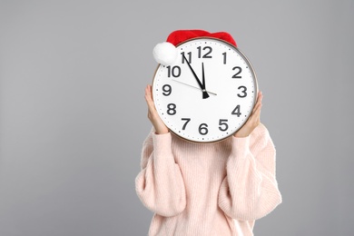 Woman with clock on grey background. New Year countdown