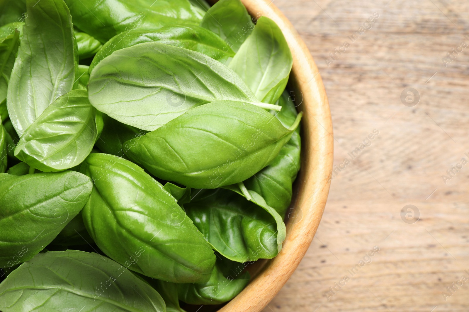 Photo of Fresh basil on wooden table, top view