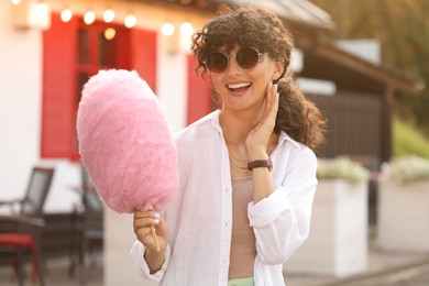 Photo of Portrait of smiling woman with cotton candy outdoors on sunny day