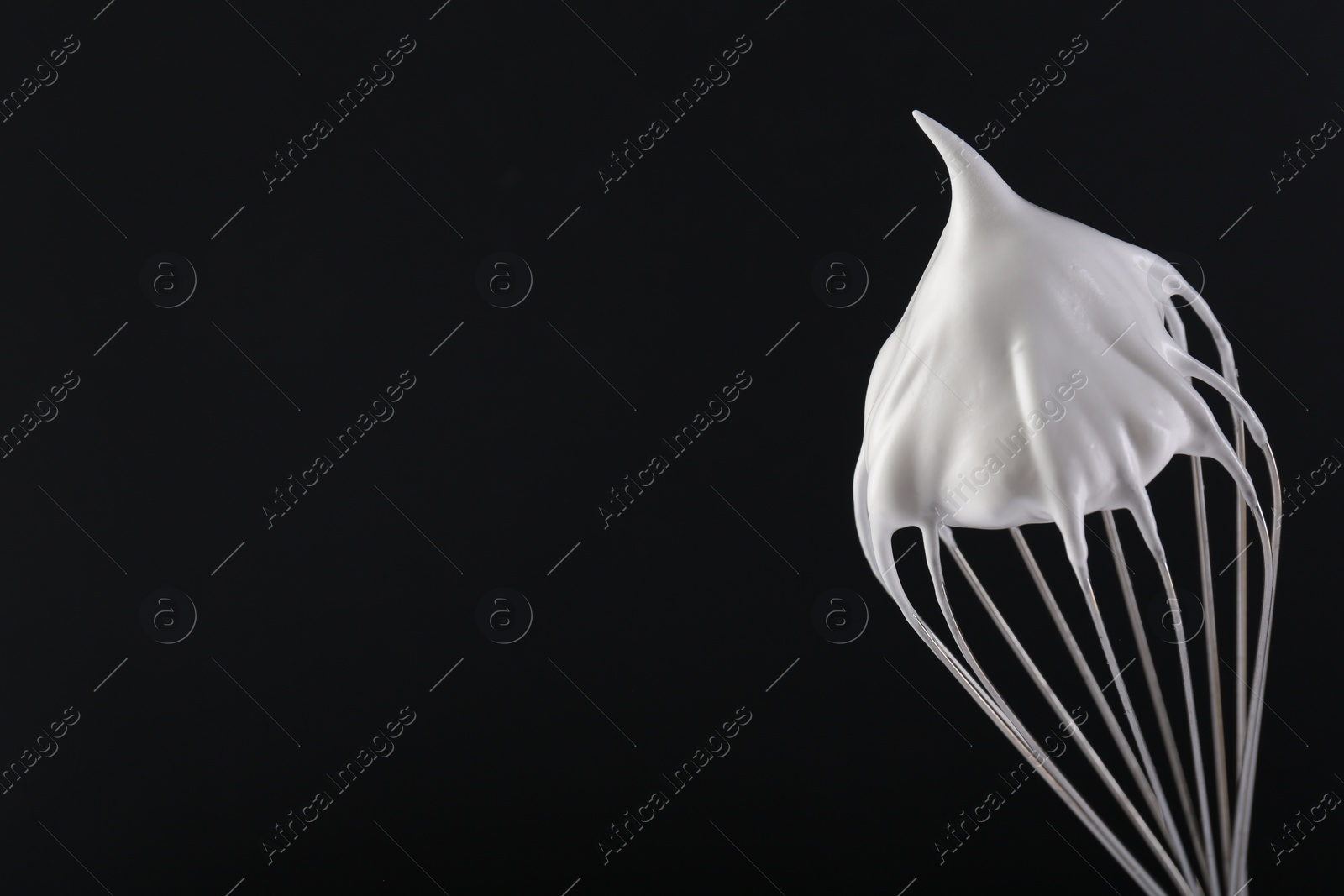 Photo of Whisk with whipped cream on black background. Space for text