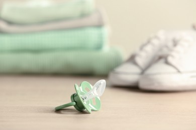 Photo of Baby pacifiers on beige table against blurred background, space for text