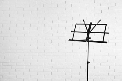 Photo of Empty music note stand near brick wall. Space for text