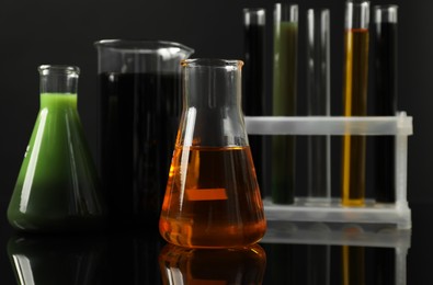 Photo of Laboratory glassware with different types of oil on black background