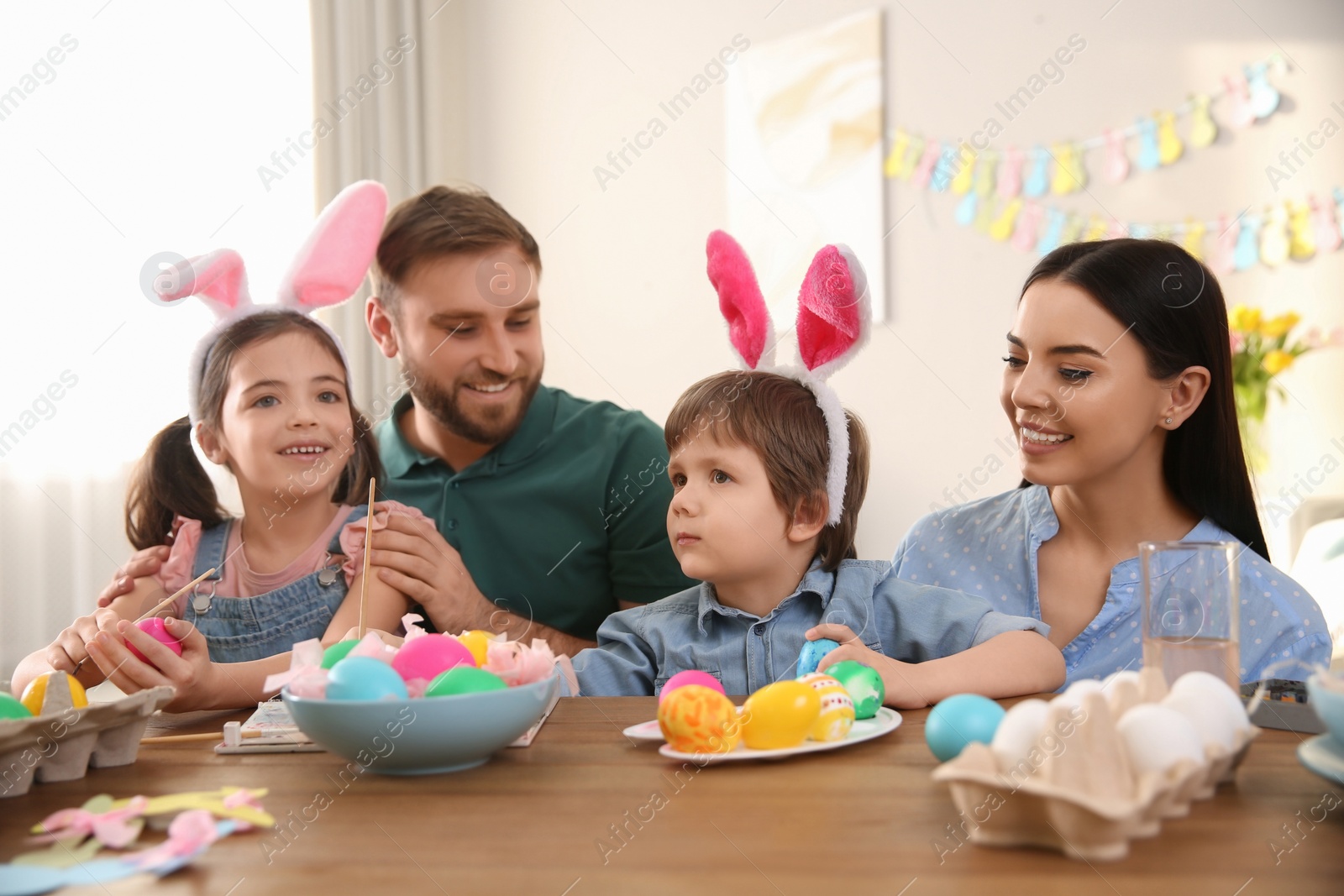 Photo of Happy family painting Easter eggs at table indoors