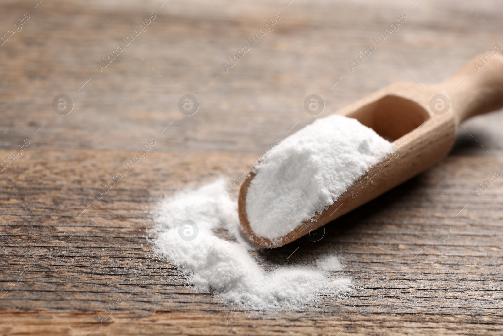 Photo of Scoop with baking soda on wooden table