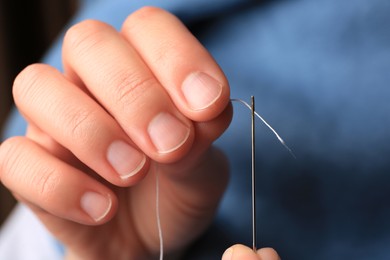 Photo of Closeup view of woman threading sewing needle
