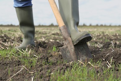 Photo of Man digging soil with shovel in field, closeup