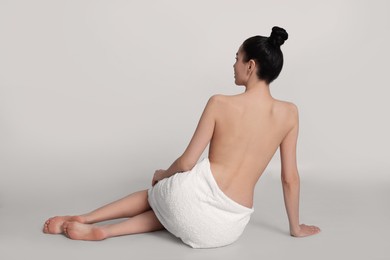 Photo of Back view of woman with perfect smooth skin sitting on light background