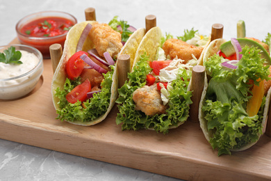 Photo of Delicious fish tacos served on grey marble table