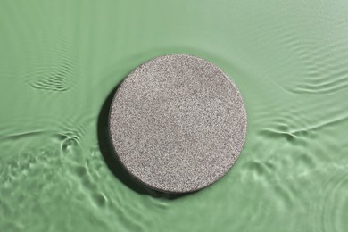 Photo of Presentation for product. Stone podium in water on green background, top view