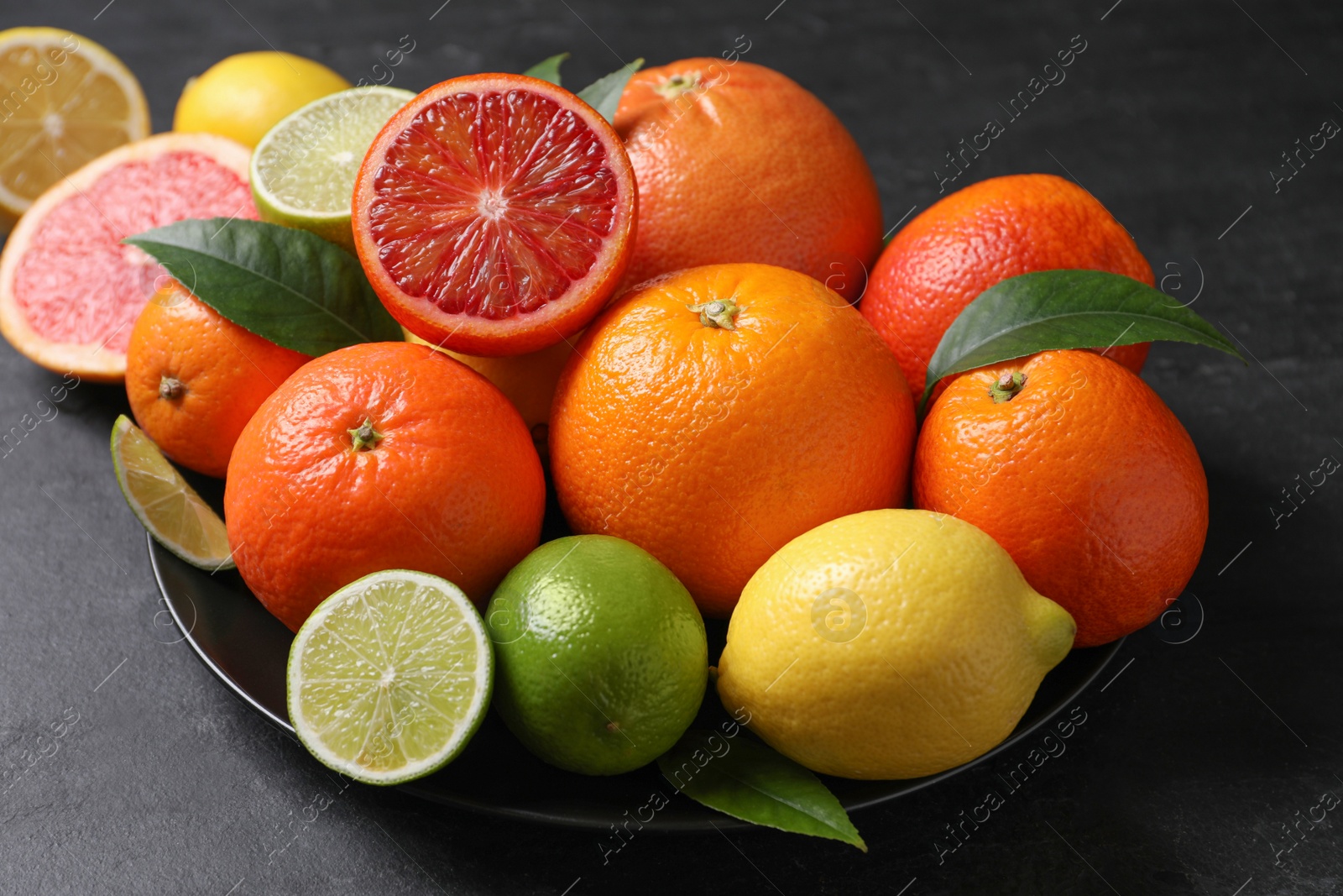 Photo of Different citrus fruits on black table, closeup