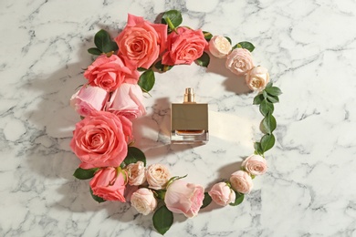 Photo of Beautiful composition with bottle of perfume and roses on marble background, flat lay