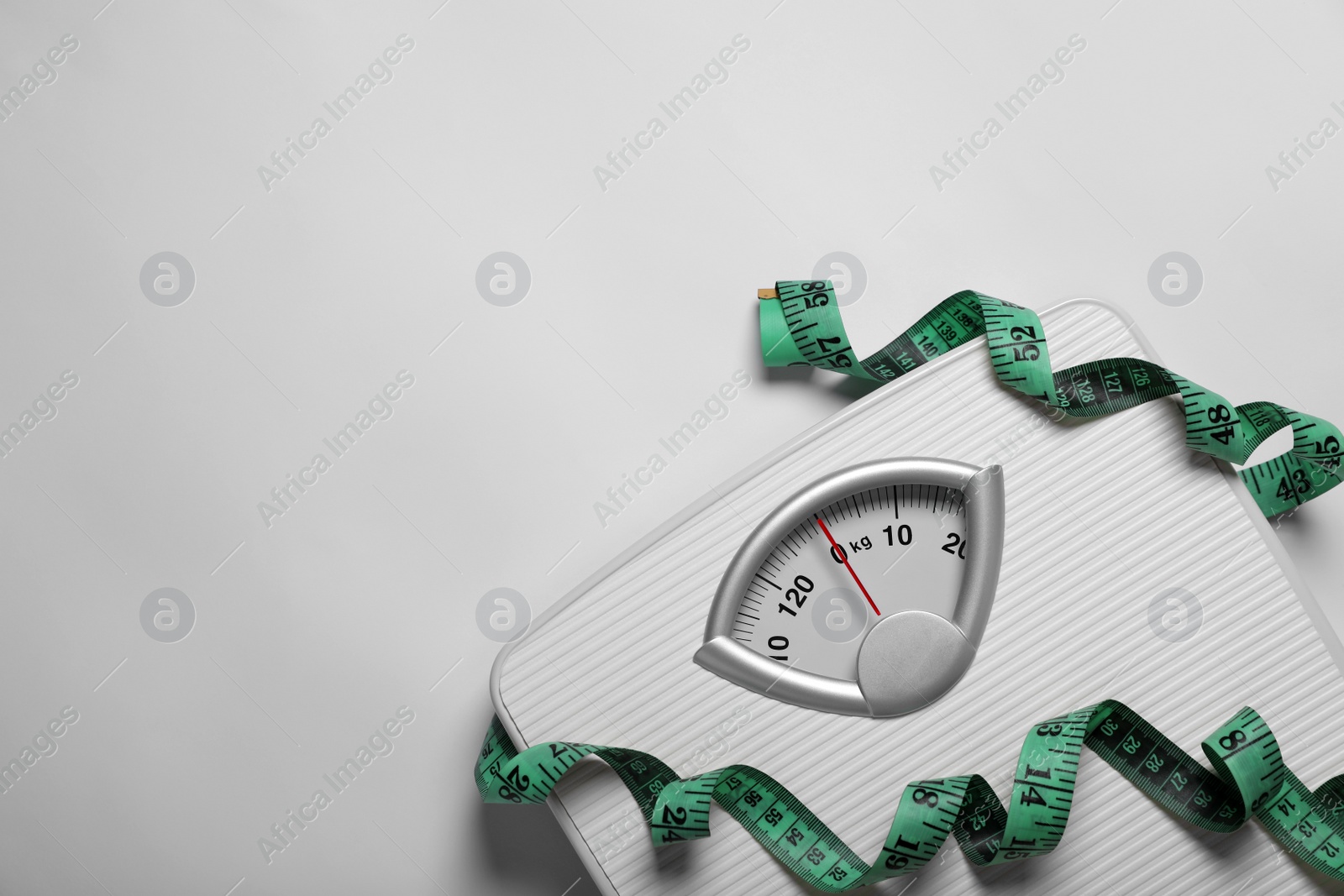 Photo of Weight loss concept. Scales and measuring tape on white background, top view. Space for text