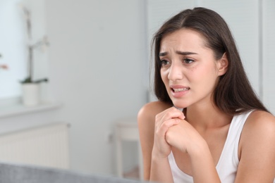 Young woman with eyelash loss problem looking in mirror indoors