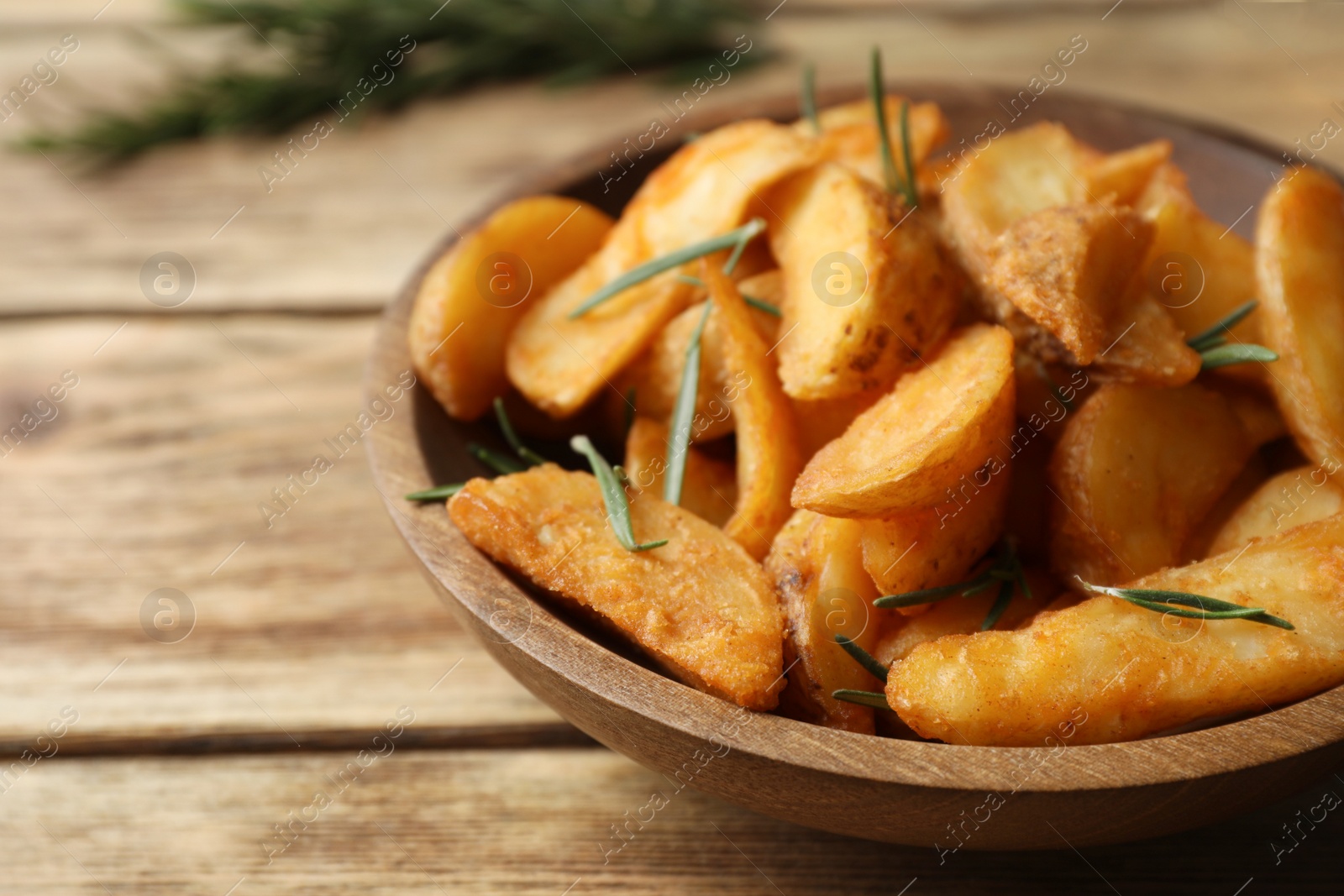 Photo of Plate with baked potatoes and rosemary on wooden table, closeup