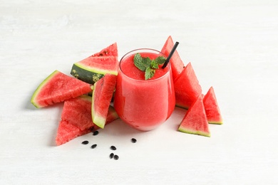 Photo of Summer watermelon drink in glass and sliced fresh fruit on table