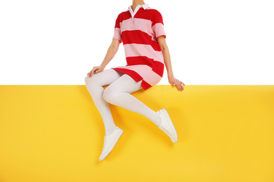 Photo of Woman wearing white tights and stylish shoes sitting on color background, closeup