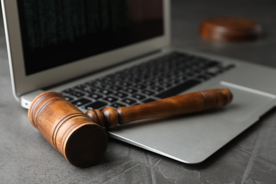 Photo of Laptop and wooden gavel on grey table, closeup. Cyber crime