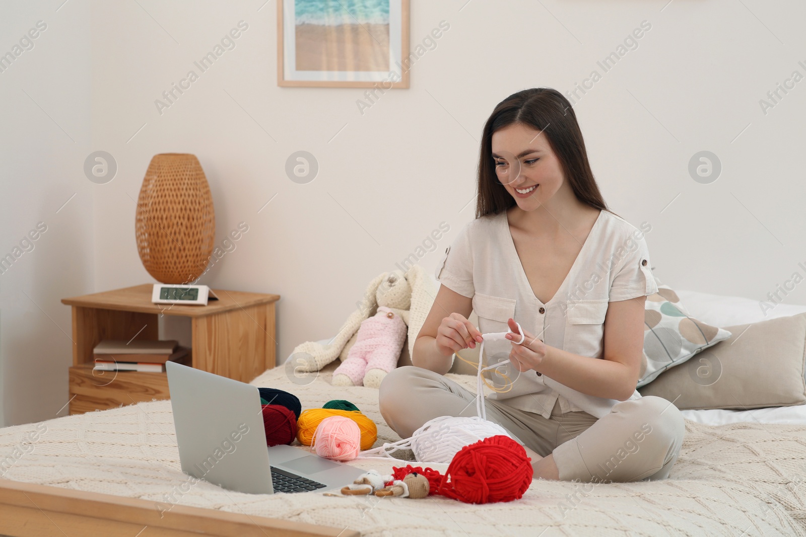 Photo of Young woman learning to knit with online course at home, space for text. Handicraft hobby