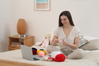 Young woman learning to knit with online course at home, space for text. Handicraft hobby