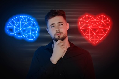 Image of Choosing between logic and emotions. Thoughtful man between glowing illustrations of heart and brain on black background