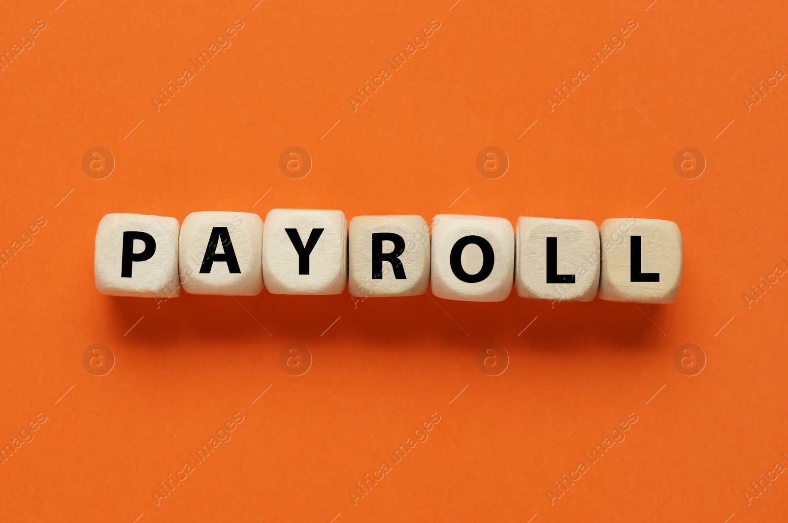 Photo of Word Payroll made of wooden cubes with letters on orange background, flat lay