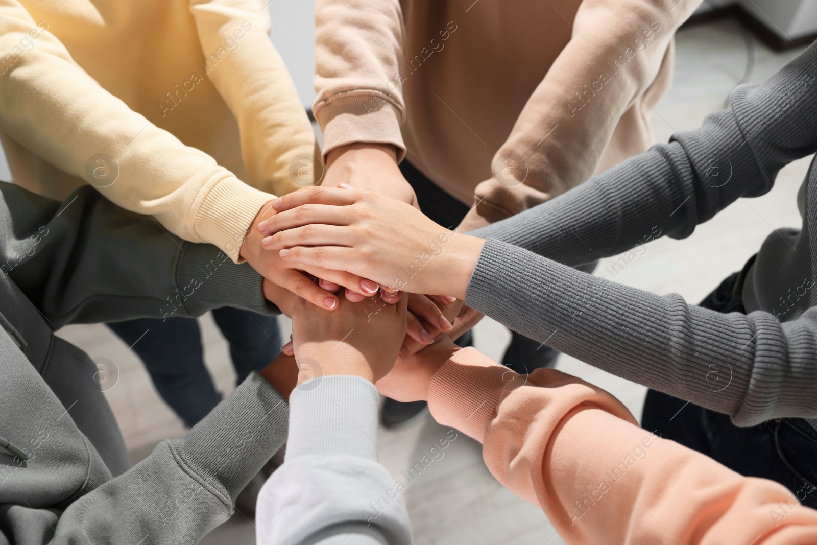 Photo of Group of people holding hands together indoors, above view. Unity concept