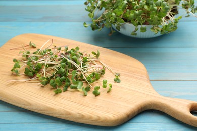 Photo of Board with cut fresh radish microgreens on light blue wooden table