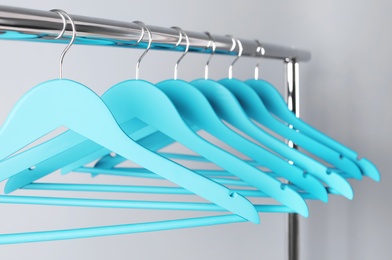 Photo of Clothes hangers on metal rack against color background