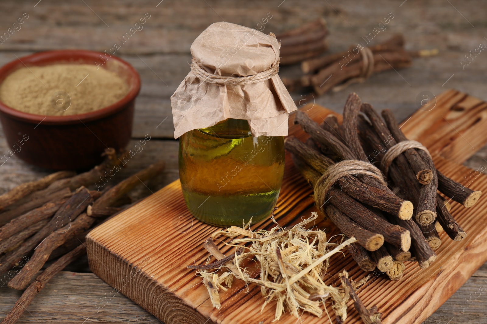 Photo of Dried sticks of licorice root, powder and essential oil on wooden table